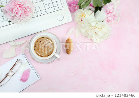 Work desk of a modern woman, home office. Computer, daisies and a cup of coffee on a pink old table. lifestyle concept, flat lay, place for text 123482466