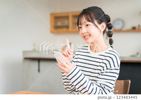 自宅のリビング・ダイニングでスマホを使う小学生・中学生の女の子 123483445