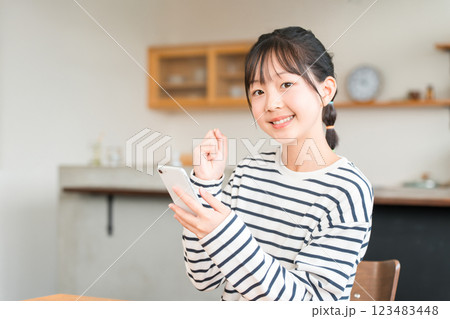 自宅のリビング・ダイニングでスマホを使う小学生・中学生の女の子 123483448
