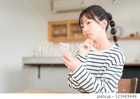 自宅のリビング・ダイニングでスマホを使う小学生・中学生の女の子 123483449
