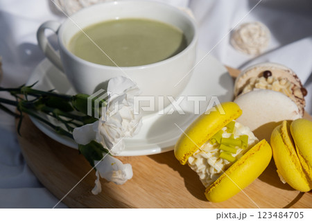 Nutrient-rich matcha drink with trendy macaron dessert on wooden tray in bed with fresh flowers. Morning beautiful breakfast present gift idea. Vibrant creative colors. Natural energy givers 123484705