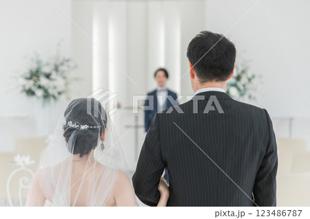 結婚式場で新郎の待つチャペルまでバージンロードを歩く新婦・花嫁の女性と父親 123486787