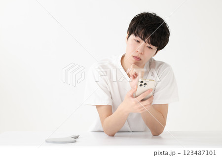 スマホを見て考える若い男性 123487101