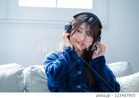 冬のリビングでヘッドホンで音楽を聴く若い女性 冬のリビングでヘッドホンで音楽を聴く若い女性 123487955