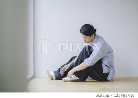 スニーカーの靴紐を結ぶアラフォーの男性 123488410
