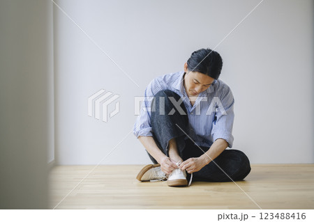 スニーカーの靴紐を結ぶアラフォーの男性 123488416