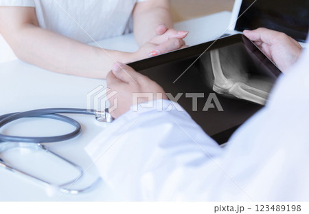 The doctor examines the patient and looks at the X-ray film of the knee. The doctor examines the patient and looks at the X-ray film of the knee. 123489198