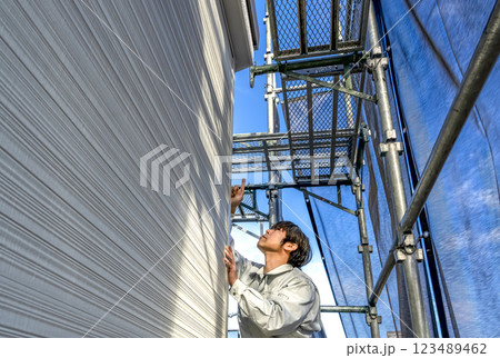 戸建て家屋の外壁修繕工事　作業状況を確認する現場監督 123489462