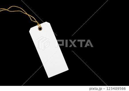 Blank paper label with cord isolated on black background. Close up of blank price label isolated. Blank paper label with cord isolated on black background. Close up of blank price label isolated. 123489566