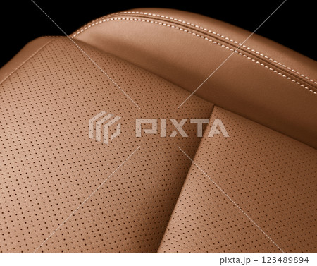 Car brownleather interior. Part of brown leather car seat details with white stitching. Interior of prestige car. Perforated leather seats isolated on black. Perforated leather. Car brownleather interior. Part of brown leather car seat details with white stitching. Interior of prestige car. Perforated leather seats isolated on black. Perforated leather. 123489894