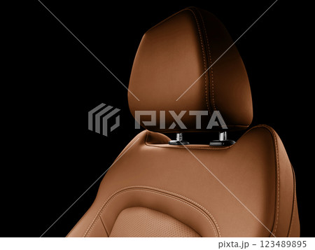 Car brown leather interior. Part of brown leather car seat details with white stitching. Interior of prestige car. Perforated leather seats isolated on black. Perforated leather. 123489895