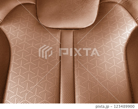 Car brown leather interior. Part of brown leather car seat details with white stitching. Interior of prestige car. Perforated leather seats isolated. Perforated leather. 123489900