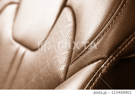 Car brown leather interior. Part of brown leather car seat details with white stitching. Interior of prestige car. Perforated leather seats isolated. Perforated leather. Car brown leather interior. Part of brown leather car seat details with white stitching. Interior of prestige car. Perforated leather seats isolated. Perforated leather. 123489901