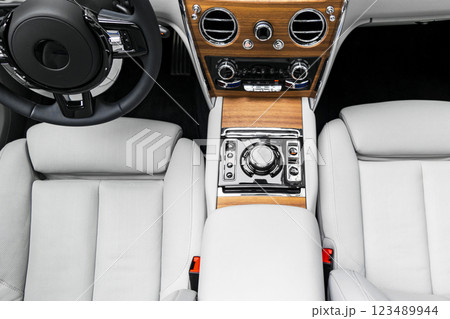 Modern luxury car white leather interior with natural wood panel. Part of leather car seat details with stitching. Interior of prestige modern car. White perforated leather. Car inside Modern luxury car white leather interior with natural wood panel. Part of leather car seat details with stitching. Interior of prestige modern car. White perforated leather. Car inside 123489944