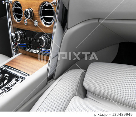 Modern luxury car white leather interior with natural wood panel. Part of leather car seat details with stitching. Interior of prestige modern car. White perforated leather. Car inside 123489949