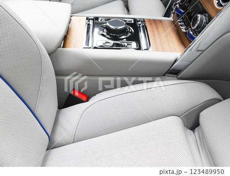 Modern luxury car white leather interior with natural wood panel. Part of leather car seat details with stitching. Interior of prestige modern car. White perforated leather. Car inside 123489950