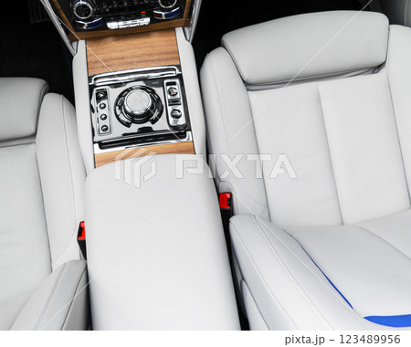 Modern luxury car white leather interior with natural wood panel. Part of leather car seat details with stitching. Interior of prestige modern car. White perforated leather. Car inside Modern luxury car white leather interior with natural wood panel. Part of leather car seat details with stitching. Interior of prestige modern car. White perforated leather. Car inside 123489956