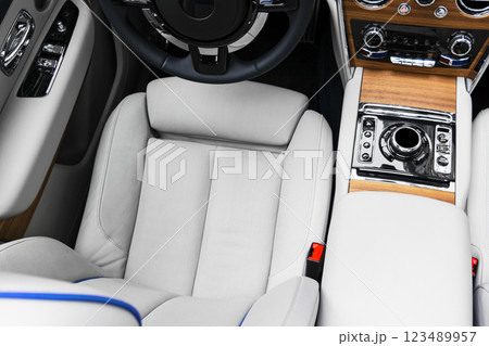 Modern luxury car white leather interior with natural wood panel. Part of leather car seat details with stitching. Interior of prestige modern car. White perforated leather. Car inside Modern luxury car white leather interior with natural wood panel. Part of leather car seat details with stitching. Interior of prestige modern car. White perforated leather. Car inside 123489957