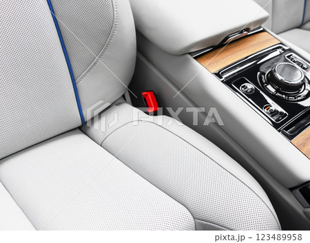 Modern luxury car white leather interior with natural wood panel. Part of leather car seat details with stitching. Interior of prestige modern car. White perforated leather. Car inside 123489958