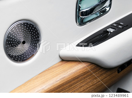 Door handle with power window control buttons of a luxury passenger car. White perforated leather interior with stitching and wood panel. Modern car interior details.. Car inside 123489961