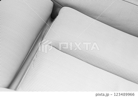 White leather interior of the luxury modern car. Perforated white leather comfortable seats with stitching. Modern car interior details. White leather interior of the luxury modern car. Perforated white leather comfortable seats with stitching. Modern car interior details. 123489966