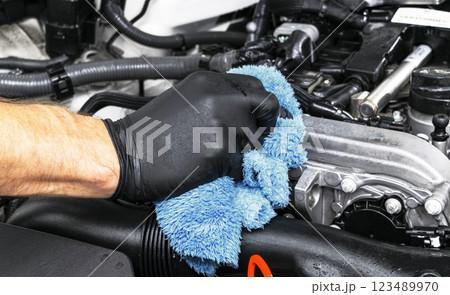 Cleaning car engine with microfiber cloth. Car detailing. Cleaning with sponge. Worker cleaning. Car wash concept Cleaning car engine with microfiber cloth. Car detailing. Cleaning with sponge. Worker cleaning. Car wash concept 123489970
