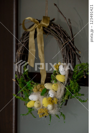 Handmade Easter wreath festive yellow egg decorations on front door. Traditional holiday preparation craft creative decor. Sustainable responsible holiday gift workshop creation. Copy space Simple 123491421