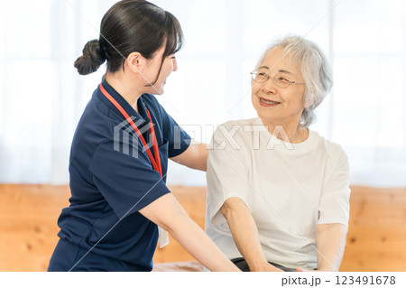 老人ホーム・介護施設にいるシニア女性と介護士・ケアマネージャーの女性スタッフ 123491678