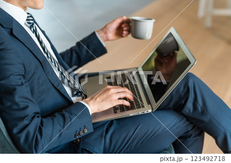ソファに座ってパソコンを操作するスーツ姿の男性ビジネスマンの手元 123492718
