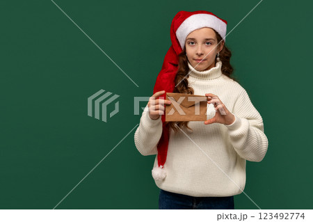 Girl in Santa hat holding brown envelope with serious expression. Girl in Santa hat holding brown envelope with serious expression. 123492774