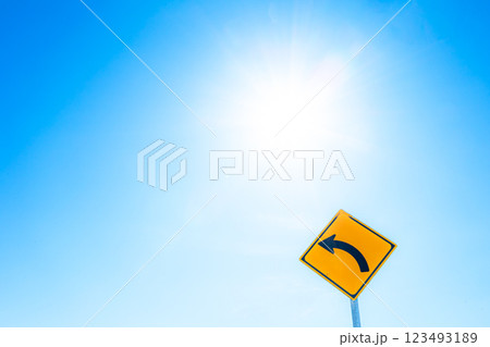 太陽の光と青空をバックに左折のカーブの標識があるイメージ風景 太陽の光と青空をバックに左折のカーブの標識があるイメージ風景 123493189