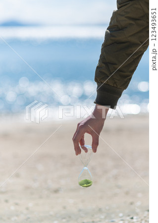 海辺で砂時計を持っている人 123493651