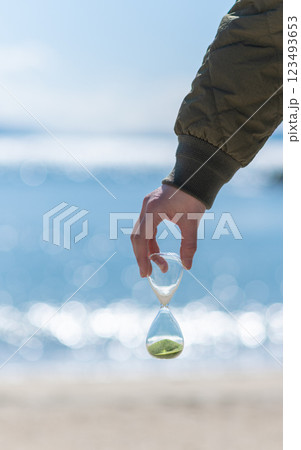 海辺で砂時計を持っている人 123493653