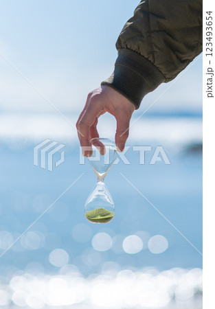 海辺で砂時計を持っている人 123493654