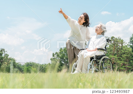 公園にいる車椅子に乗ったシニア女性と介助する女性(介護・親子・老人ホーム) 公園にいる車椅子に乗ったシニア女性と介助する女性(介護・親子・老人ホーム) 123493987
