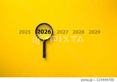 Magnifying glass focusing on year 2026 among other years on yellow background Magnifying glass focusing on year 2026 among other years on yellow background 123494700