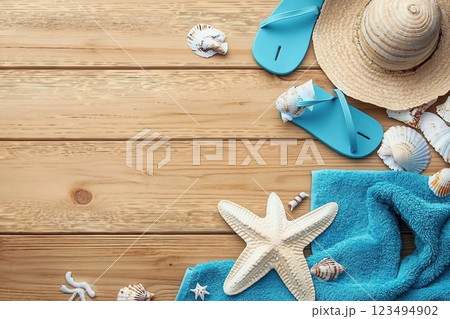 Different seashells with towels and flip flops on brown wooden table Different seashells with towels and flip flops on brown wooden table 123494902