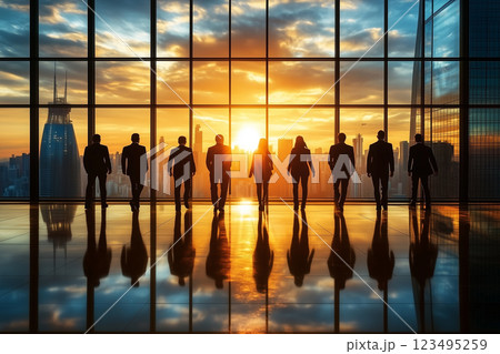 オフィスビルで夕日と都市風景を見つけるビジネスチームのシルエット 123495259