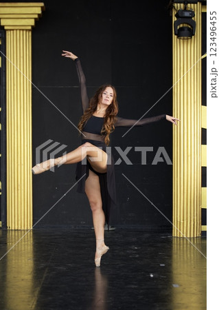 Ballet Dancer in Black Dress Performing Graceful Pose on Stage  123496455