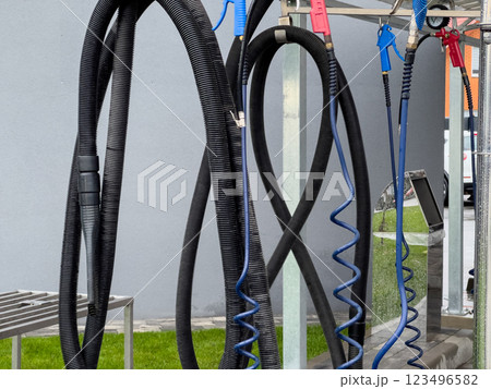 A variety of high-pressure car washer guns hang at a car wash. These essential tools are organized and ready for work, demonstrating efficient cleaning for vehicles 123496582