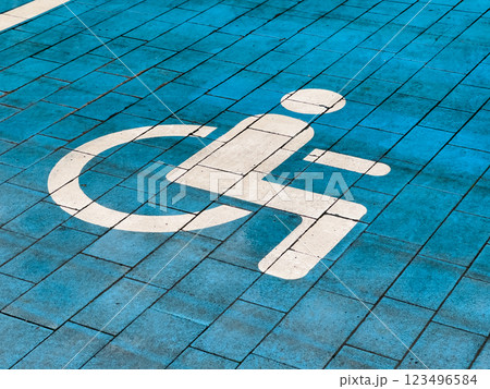A designated parking spot for disabled individuals is clearly marked on the ground with a white symbol against a blue pavement surface, ensuring accessibility for all 123496584