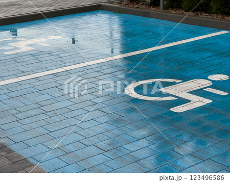 A designated parking space for disabled individuals features a blue pavement with a white wheelchair symbol clearly marked. This ensures accessibility and convenience A designated parking space for disabled individuals features a blue pavement with a white wheelchair symbol clearly marked. This ensures accessibility and convenience 123496586