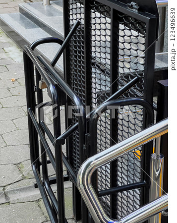A metallic ramp is installed next to a set of stairs, ensuring accessibility for individuals with mobility challenges in a public area 123496639