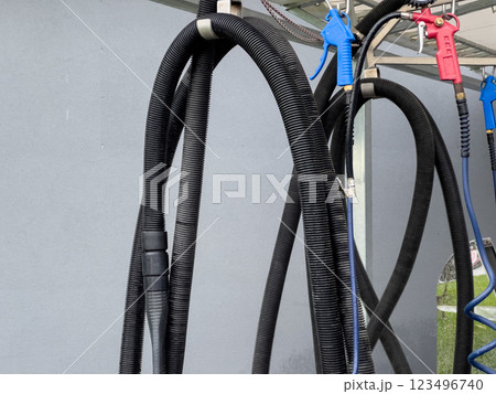 High pressure car washer guns and hoses are neatly organized at a car wash station, ready for use during busy service hours, ensuring efficient cleaning 123496740