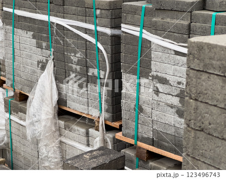 Cobblestones are organized in tall stacks, securely wrapped and prepared for delivery, showcasing their various textures and shades under bright daylight 123496743