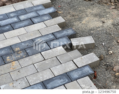 Workers carefully lay the paving stones in a pattern to construct a robust pavement at a construction site, ensuring precise alignment for durability 123496750