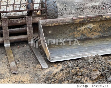 A compact loader equipped with a bucket attachment rests on a construction site, surrounded by dirt and rocks, awaiting the next earthmoving job 123496753