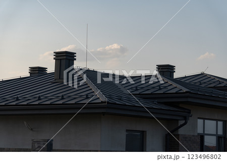 This rooftop features sleek metal tiles and multiple chimneys, emphasizing a modern architectural style. The backdrop includes a calming evening sky, enhancing the aesthetic appeal This rooftop features sleek metal tiles and multiple chimneys, emphasizing a modern architectural style. The backdrop includes a calming evening sky, enhancing the aesthetic appeal 123496802