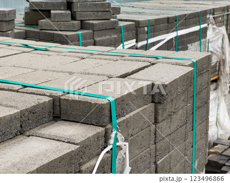 Gray brick pavers are neatly stacked and secured with plastic wraps, waiting for installation on a city sidewalk. The setup indicates ongoing urban development activities Gray brick pavers are neatly stacked and secured with plastic wraps, waiting for installation on a city sidewalk. The setup indicates ongoing urban development activities 123496866