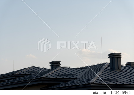 The rooftops of stylish homes rise under a peaceful sky, featuring sleek metal tile designs. These architectural elements reflect the warmth of the afternoon sun The rooftops of stylish homes rise under a peaceful sky, featuring sleek metal tile designs. These architectural elements reflect the warmth of the afternoon sun 123496960